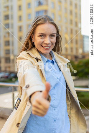 Happy mature Caucasian woman showing thumb up gives positive reply standing on downtown city street 128658838