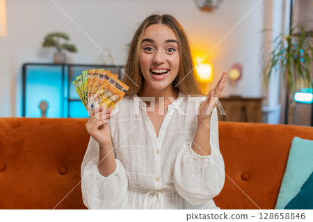 Successful rich happy smiling woman holding waving euro bills money fan winning online lottery game Successful rich happy smiling woman holding waving euro bills money fan winning online lottery game 128658846