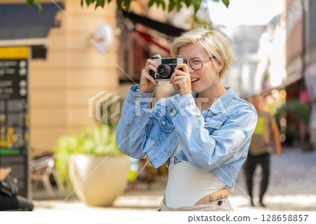 Portrait of happy young woman tourist traveler taking photos using retro camera on city urban street Portrait of happy young woman tourist traveler taking photos using retro camera on city urban street 128658857