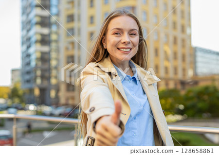 Happy mature Caucasian woman showing thumb up gives positive reply standing on downtown city street Happy mature Caucasian woman showing thumb up gives positive reply standing on downtown city street 128658861