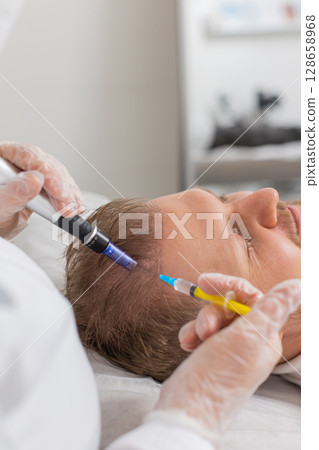 Trichologist doing man improve hair growth procedure, dermapen microneedling, vitamin injections 128658968