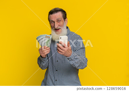 Happy senior man use smartphone rejoicing game win receiving money dollar cash celebrating success 128659016