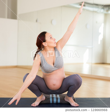 Pregnant woman is engaged in yoga. Deep Squats or Mama Squats or Malasana 128660988