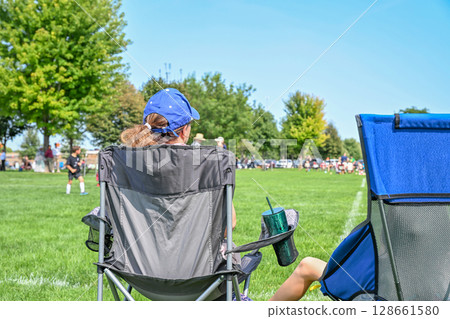 Parents enjoy a sunny day at a youth soccer match while supporting their kids on the field 128661580
