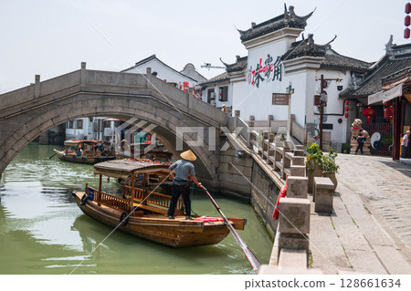 Chinese waterman paddle boat to bridge to city god temple, Zhujiajiao 128661634