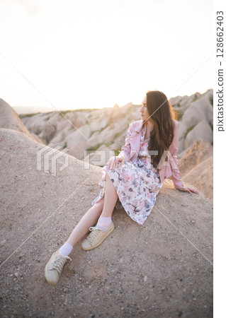 a beautiful girl walks on the top of the mountain enjoying the view 128662403