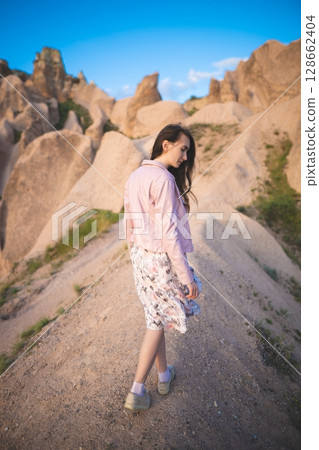 a beautiful girl walks on the top of the mountain enjoying the view 128662404