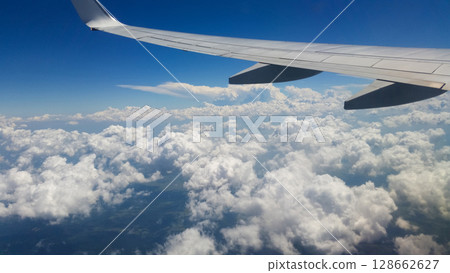 beautiful thick clouds in the sky from the height of the flight of the plane with a view of the wing with engines 128662627