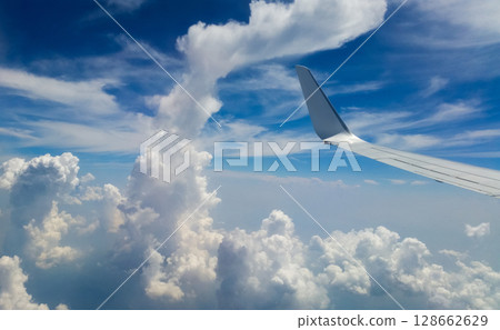beautiful thick clouds in the sky from the height of the flight of the plane with a view of the wing with engines 128662629