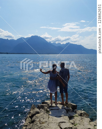 a couple in love is standing on a pier admiring the sea a couple in love is standing on a pier admiring the sea 128662651