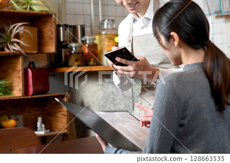 Asian male waiter serving customers at a restaurant 128663535