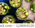 Homemade Pickled Cucumbers in Glass Jars with Spices and Herbs 128664526
