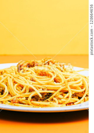 A classic plate of spaghetti with a rich, savory meat sauce, served on a white dish against an orange background. A classic plate of spaghetti with a rich, savory meat sauce, served on a white dish against an orange background. 128664656
