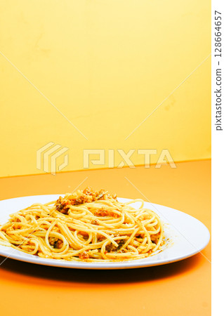 A classic plate of spaghetti with a rich, savory meat sauce, served on a white dish against an orange background. A classic plate of spaghetti with a rich, savory meat sauce, served on a white dish against an orange background. 128664657
