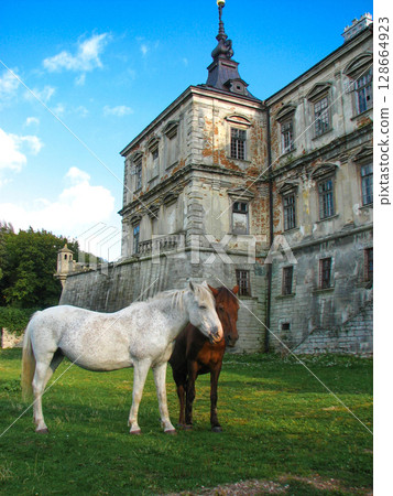 two beautiful horses in love against the background of an ancient castle two beautiful horses in love against the background of an ancient castle 128664923
