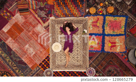a beautiful girl in dress in a traditional turkish interior with many carpets on the wall a beautiful girl in dress in a traditional turkish interior with many carpets on the wall 128665279