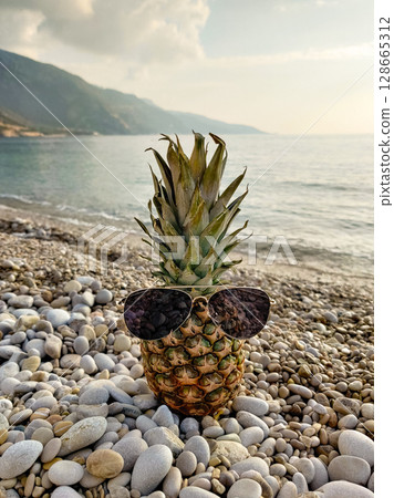 close up of a beautiful fresh pineapple on the beach wearing sunglasses close up of a beautiful fresh pineapple on the beach wearing sunglasses 128665312