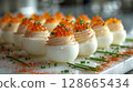 Caviar Deviled Eggs float elegantly, showcasing creamy yolk filling, caviar, chives, and paprika, emphasizing their luxurious and gourmet appeal. 128665434