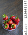 top view several fresh strawberries Placed in a clear plastic glass lid on a wooden table background, fruit, health, food, copy space 128665467