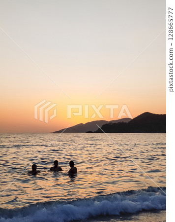 silhouette of children to swim in the sea at sunset 128665777