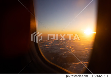 beautiful thick clouds in the sky from the height of the flight of the plane with a view of the wing with engines through the round window 128665901