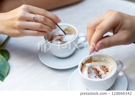 close-up of the hands of a couple in love enjoying morning coffee close-up of the hands of a couple in love enjoying morning coffee 128666342