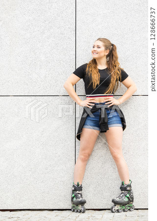 Young woman riding roller skates 128666737