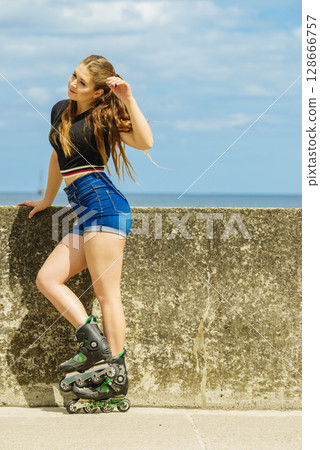 Happy young woman wearing roller skates Happy young woman wearing roller skates 128666757