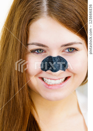 Woman applying pore strips on nose 128666836