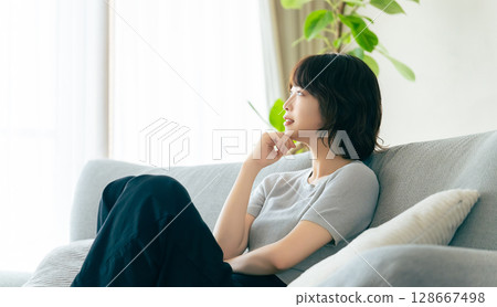 坐在客廳沙發上微笑的女人 坐在客廳沙發上微笑的女人 128667498