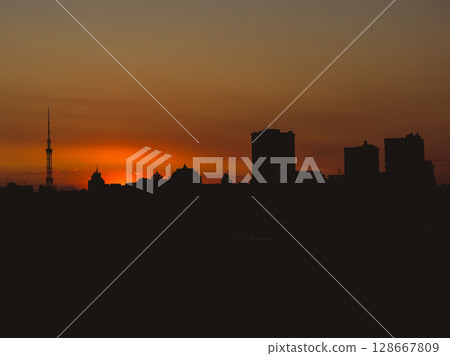 Dramatic urban skyline silhouette against a fiery sunset Dramatic urban skyline silhouette against a fiery sunset 128667809