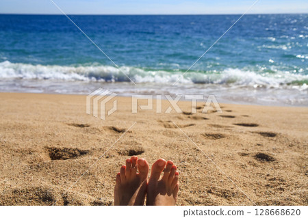 beautiful landscape on the coast of the beach and sea waves against the background of the blue sky and human legs 128668620
