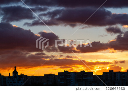 beautiful colored sky and thick clouds at sunset on the horizon city silhouette 128668680