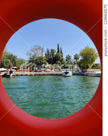 red lifebuoy on a boat swimmers in a pond 128668870