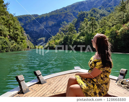 beautiful girl on the deck of a boat while traveling on the sea with a view of the mountains 128668880