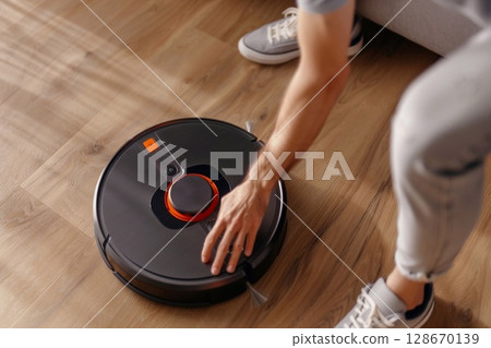 A man fixes a robot vacuum cleaner A man fixes a robot vacuum cleaner 128670139
