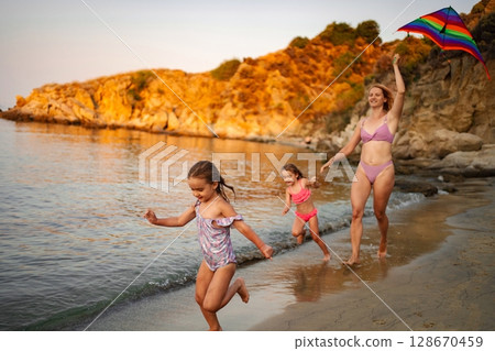 Family beach day with a sunset and colorful kites Family beach day with a sunset and colorful kites 128670459