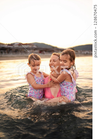 Joyful moments of a family playing together at sunset by the sea 128670475