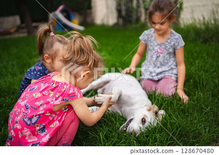 Joyful children playing with a friendly dog in a sunny garden 128670480