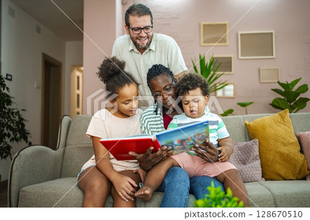 Family bonding over story time in a cozy living room 128670510