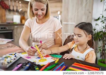 Mother and daughter engage in creative drawing during a playful afternoon at home 128670570