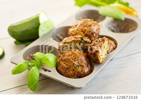 Vegetarian zucchini muffins in a bright presentation on a light wooden table Vegetarian zucchini muffins in a bright presentation on a light wooden table 128671016