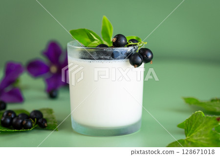 Natural yogurt with blackcurrant on a bright green background 128671018