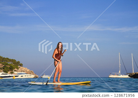 a beautiful girl swims on a sap on the sea 128671956