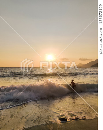 silhouette of children to swim in the sea at sunset silhouette of children to swim in the sea at sunset 128672199
