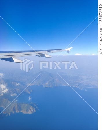beautiful thick clouds in the sky from the height of the flight of the plane with a view of the wing with engines 128672210