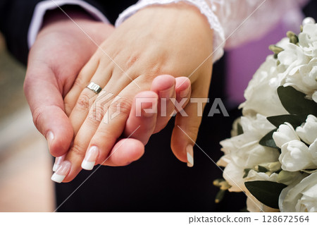 close-up of a couple in love holding hands with wedding rings close-up of a couple in love holding hands with wedding rings 128672564