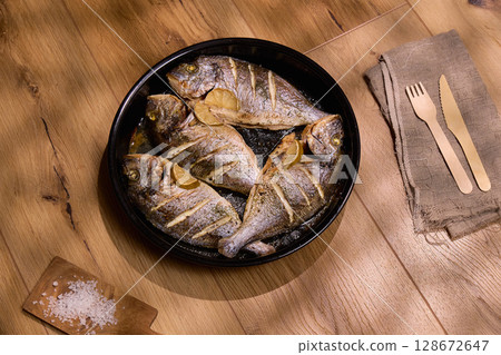 Juicy dorado fish are presented on a dark platter, garnished with herbs and a sprinkle of salt. Juicy dorado fish are presented on a dark platter, garnished with herbs and a sprinkle of salt. 128672647