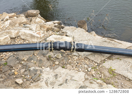 Large diameter irrigation water pipe going into a river 128672808