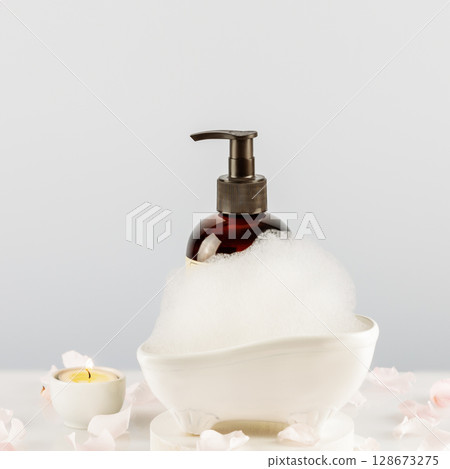 Spa relax composition with cosmetic bottle, soap foam, candles and rose petals on white table. Wellness and skin care treatment. Mockup of beauty product. Concept of me time and self care Spa relax composition with cosmetic bottle, soap foam, candles and rose petals on white table. Wellness and skin care treatment. Mockup of beauty product. Concept of me time and self care 128673275